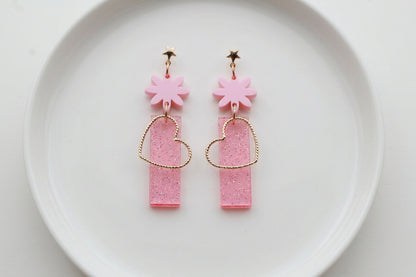 Pink Ines floral heart dangle earrings arranged on a white plate