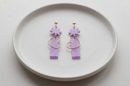 Purple Ines floral heart dangle earrings arranged on a white plate