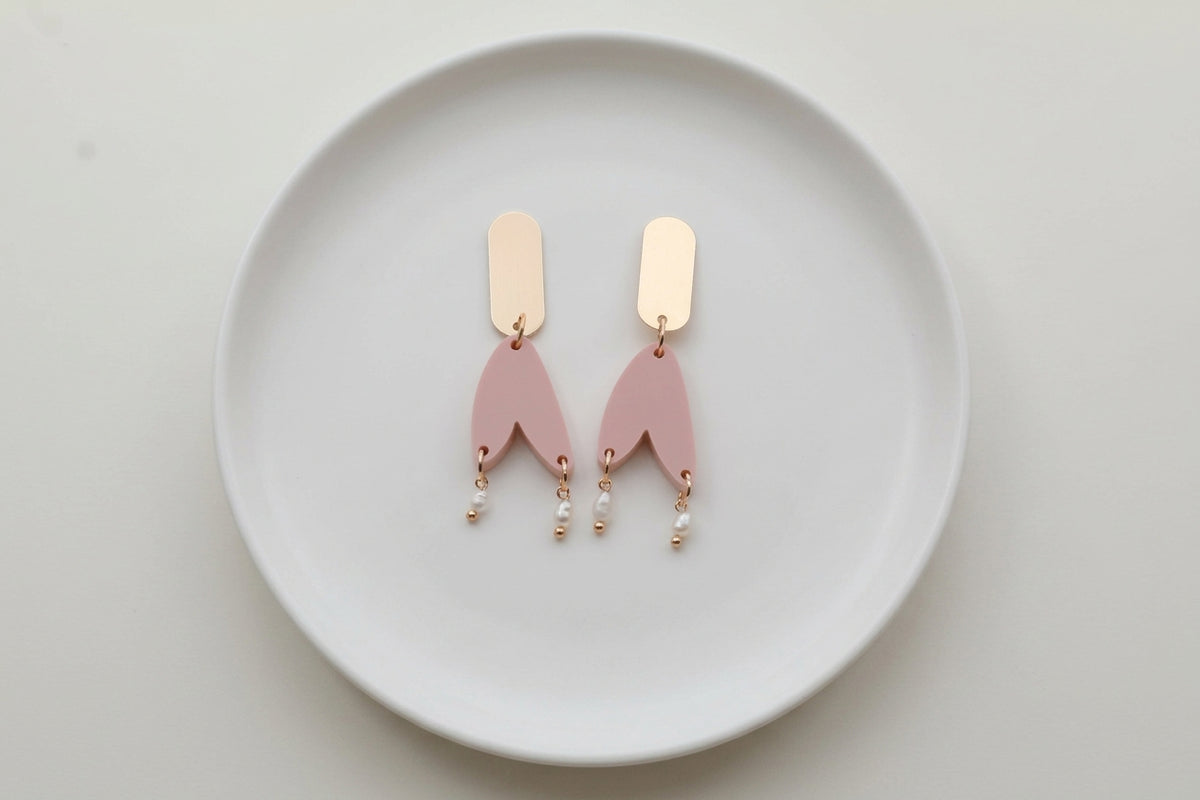 Beige Iris geometric long drop earrings arranged on a white plate