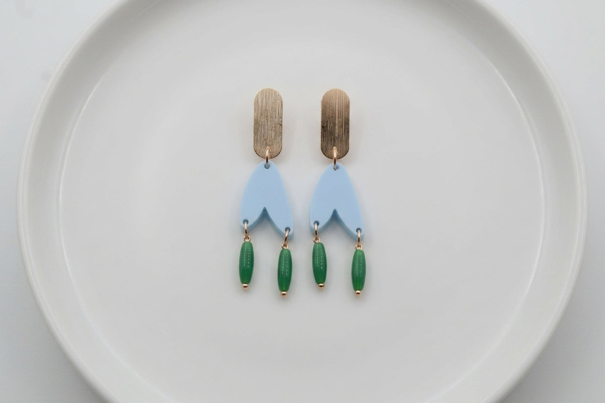 Blue Iris geometric long drop earrings arranged on a white plate