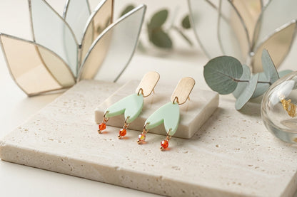 Green Iris geometric long drop earrings in a styled product setting