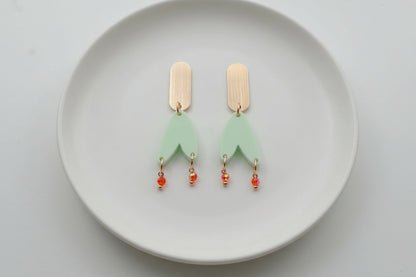 Green Iris geometric long drop earrings arranged on a white plate
