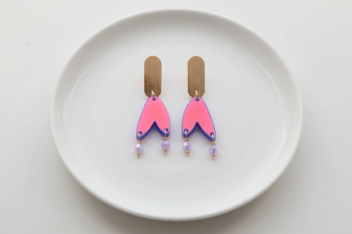 HB Iris geometric long drop earrings arranged on a white plate