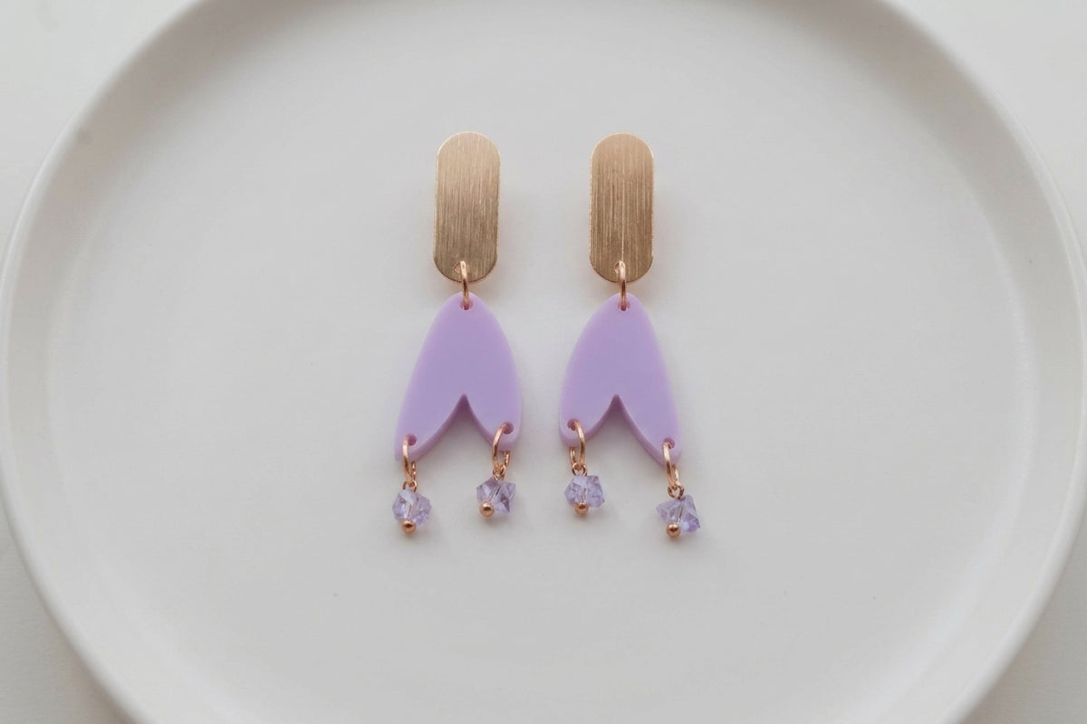 Purple Iris geometric long drop earrings arranged on a white plate