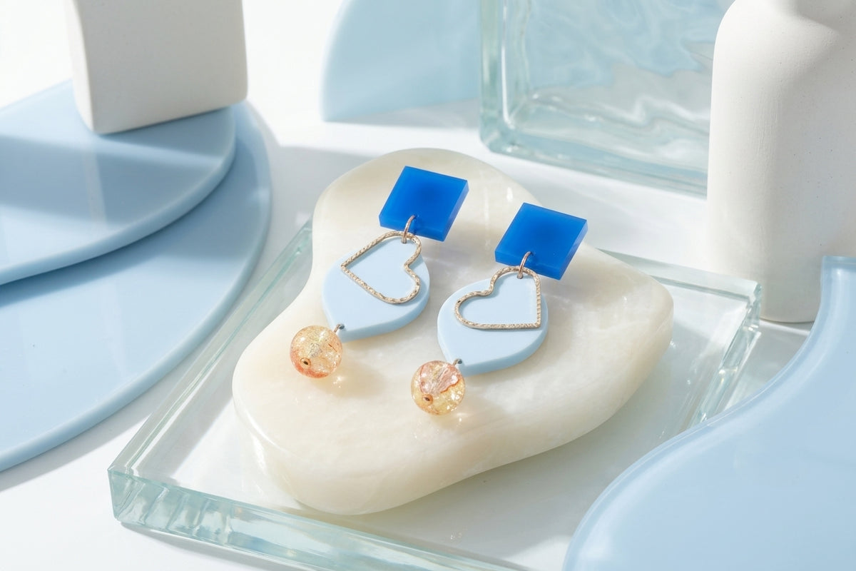 Blue Lara heart acrylic dangle earrings in a styled product setting