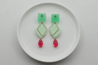 Green Lara heart acrylic dangle earrings arranged on a white plate