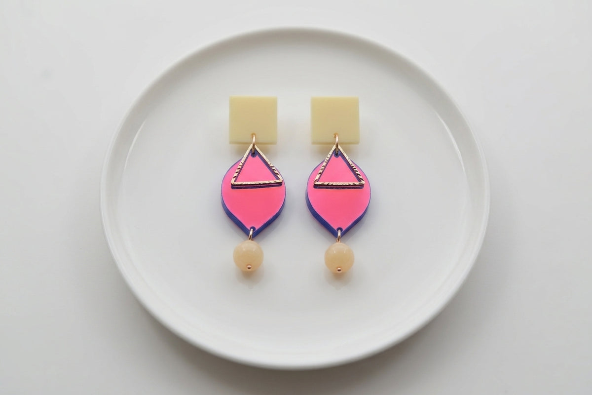 HB Lara heart acrylic dangle earrings arranged on a white plate