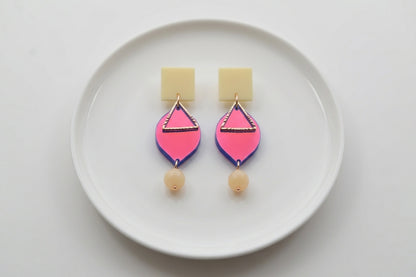 HB Lara heart acrylic dangle earrings arranged on a white plate