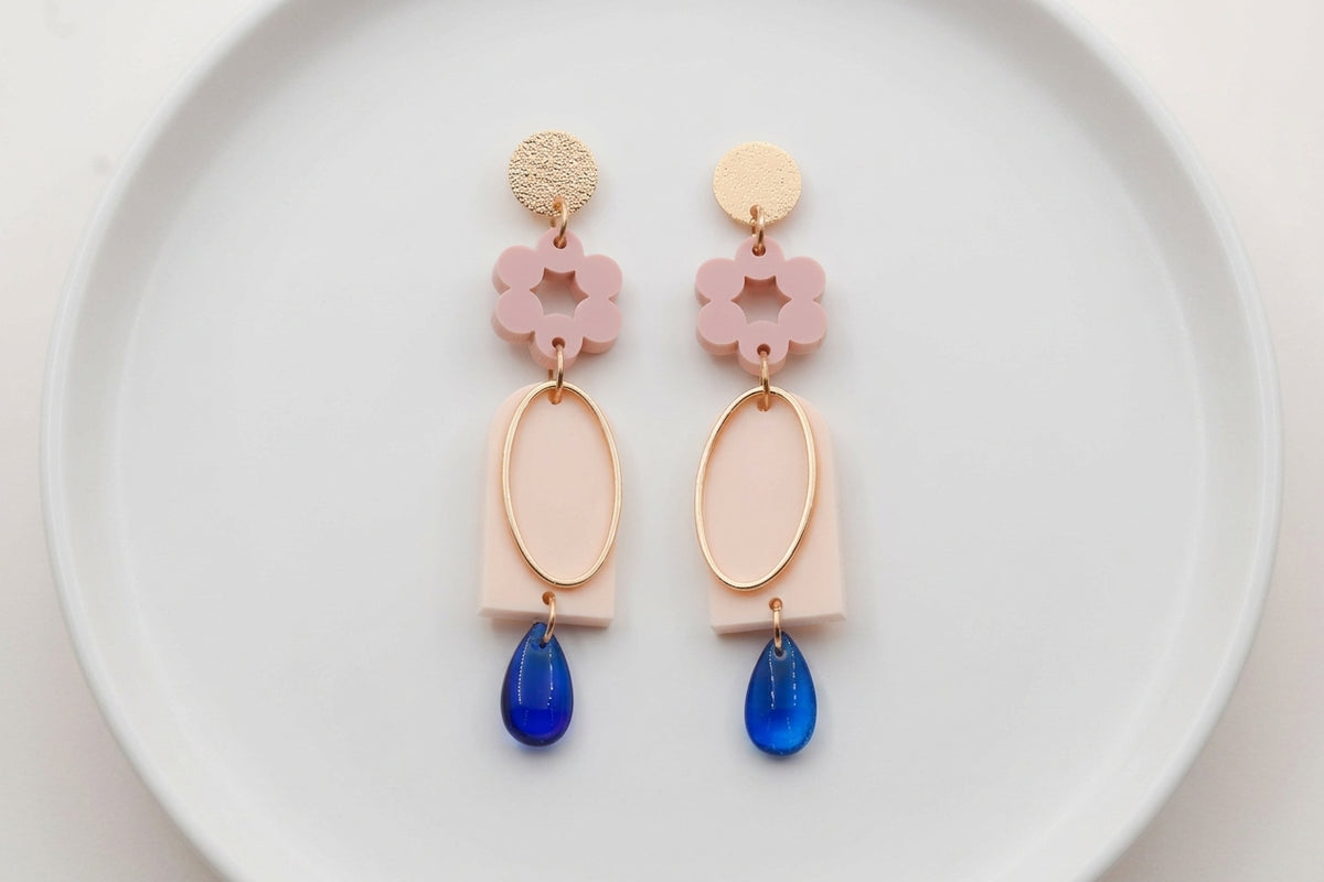 Beige Lena floral long drop earrings arranged on a white plate