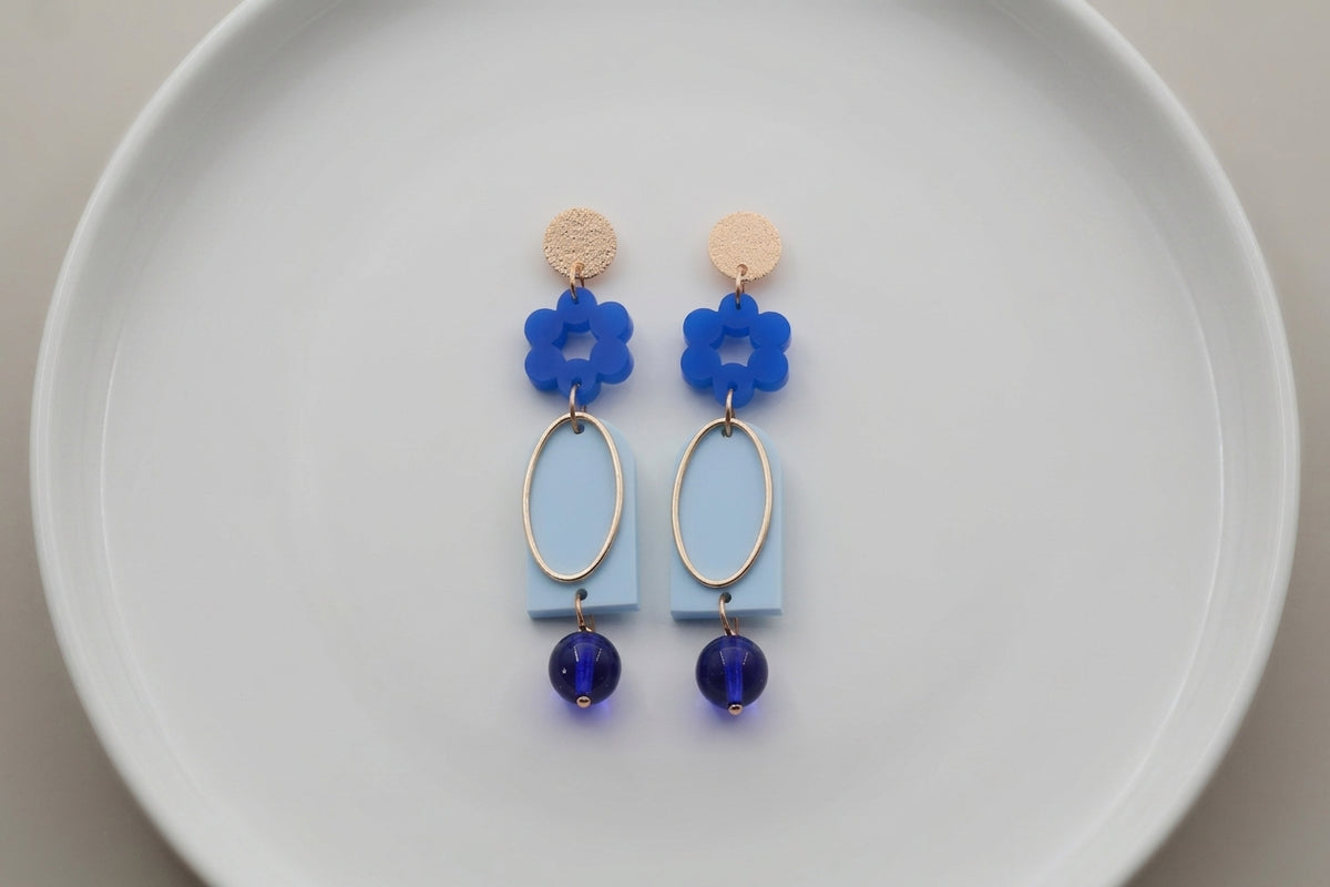 Blue Lena floral long drop earrings arranged on a white plate