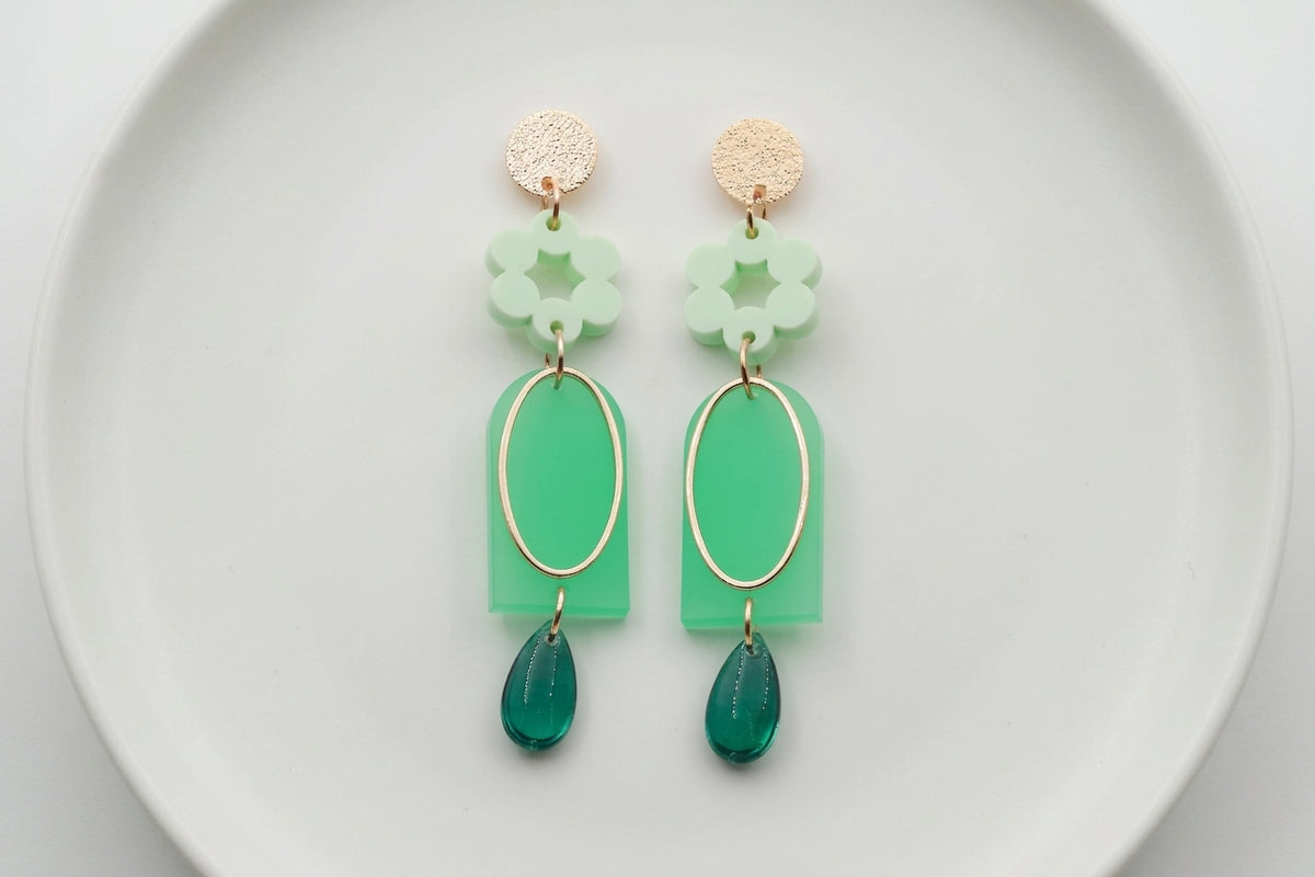 Green Lena floral long drop earrings arranged on a white plate