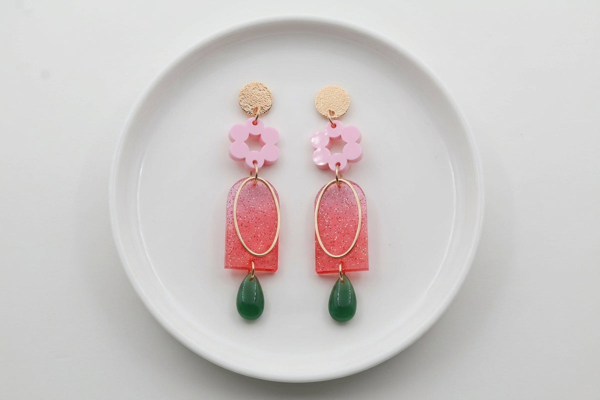 Pink Lena floral long drop earrings arranged on a white plate