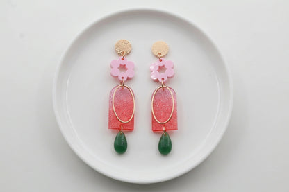Pink Lena floral long drop earrings arranged on a white plate