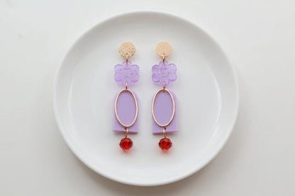 Purple Lena floral long drop earrings arranged on a white plate