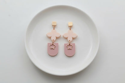 Beige Lia floral heart drop earrings arranged on a white plate