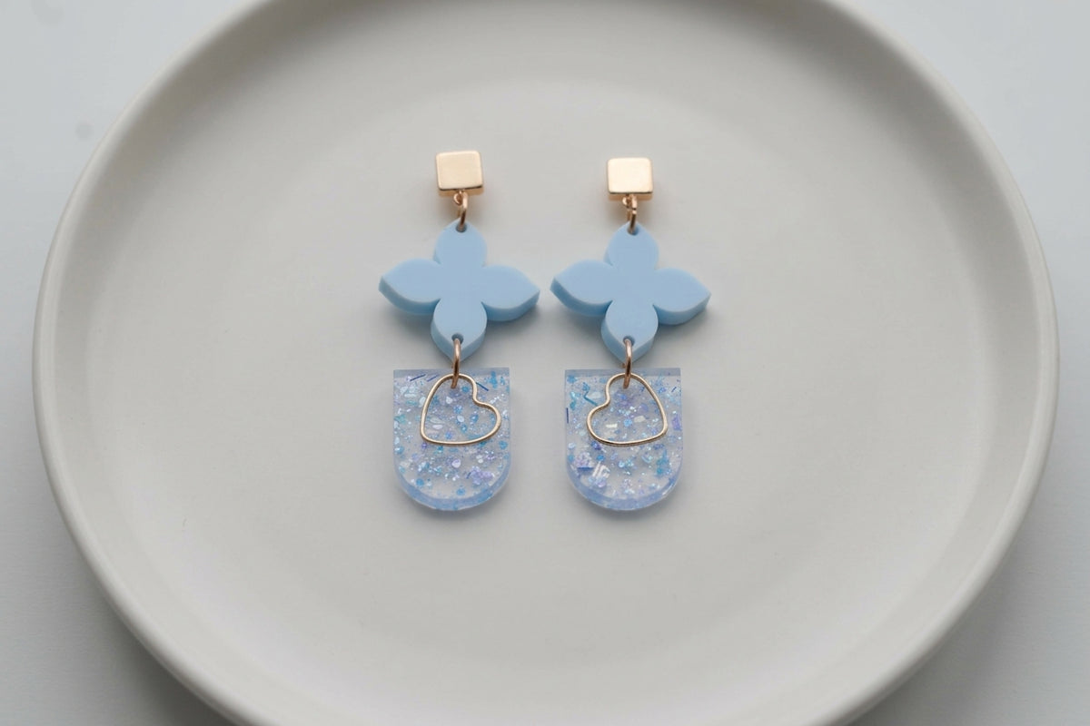 Blue Lia floral heart drop earrings arranged on a white plate
