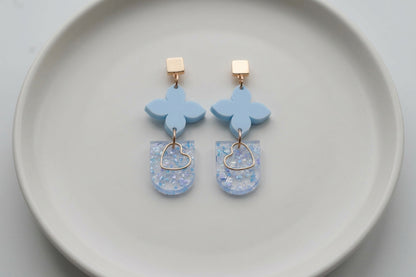Blue Lia floral heart drop earrings arranged on a white plate