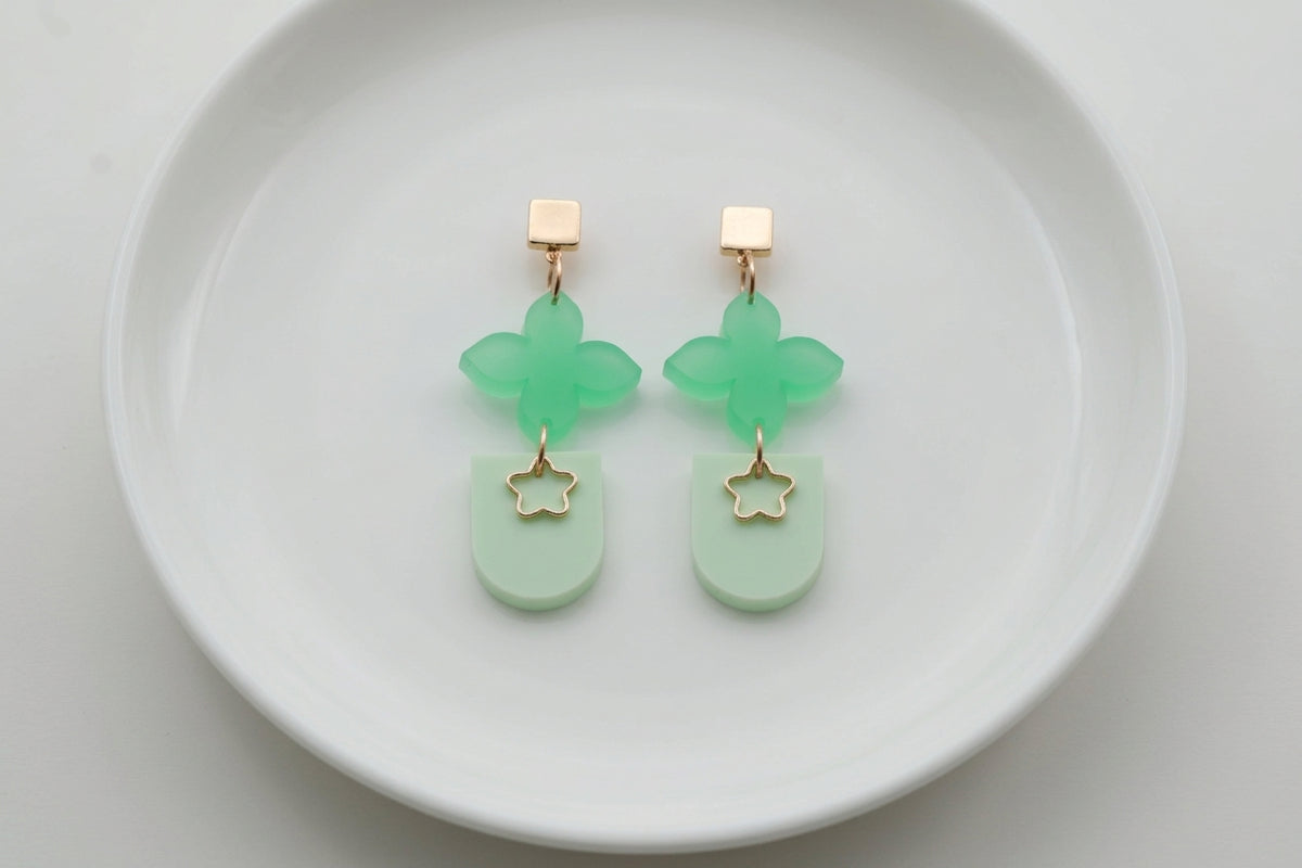 Green Lia floral heart drop earrings arranged on a white plate