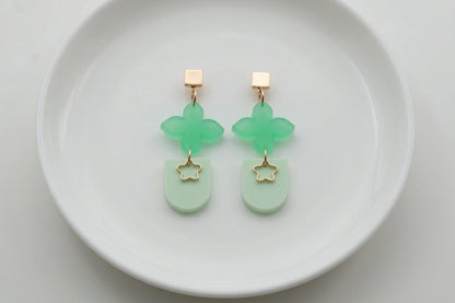 Green Lia floral heart drop earrings arranged on a white plate