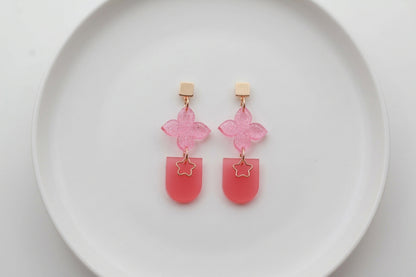 Pink Lia floral heart drop earrings arranged on a white plate