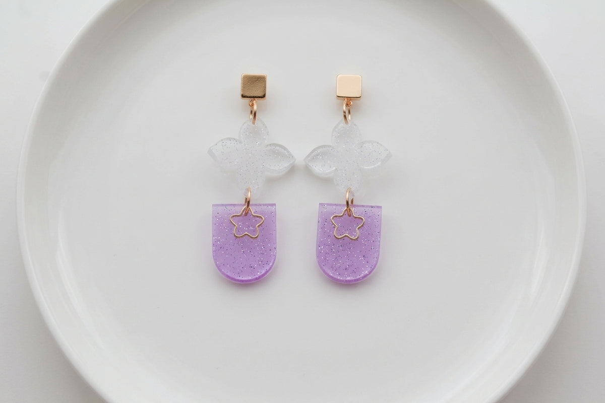 Purple Lia floral heart drop earrings arranged on a white plate