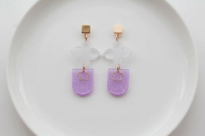 Purple Lia floral heart drop earrings arranged on a white plate