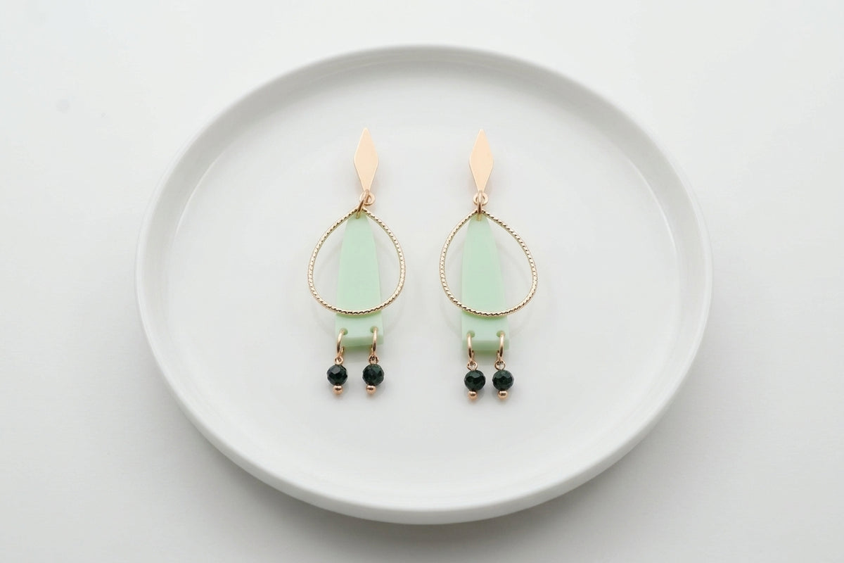 Green Lina long geometric acrylic earrings arranged on a white plate