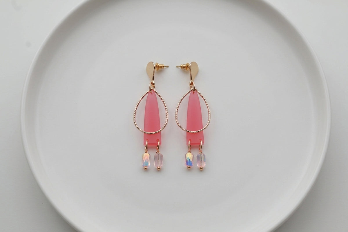 Pink Lina long geometric acrylic earrings arranged on a white plate