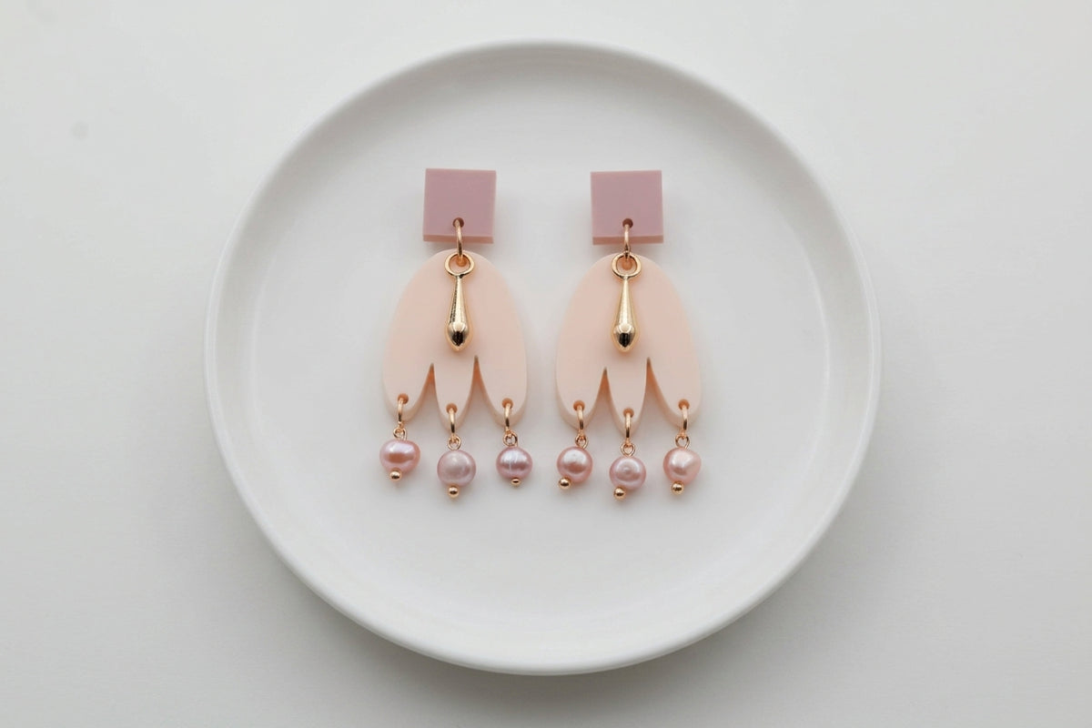 Beige Liv acrylic beaded statement earrings arranged on a white plate