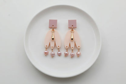 Beige Liv acrylic beaded statement earrings arranged on a white plate