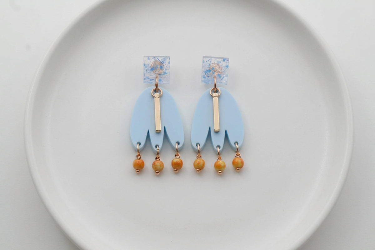 Blue Liv acrylic beaded statement earrings arranged on a white plate