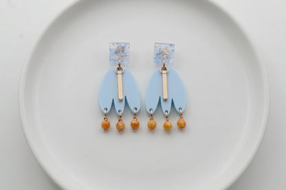 Blue Liv acrylic beaded statement earrings arranged on a white plate