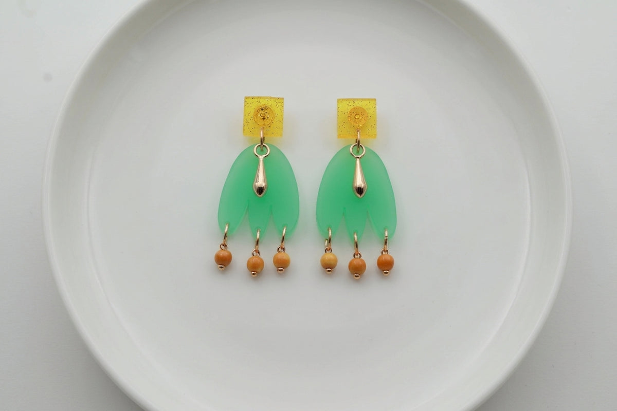 Green Liv acrylic beaded statement earrings arranged on a white plate