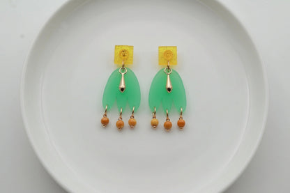 Green Liv acrylic beaded statement earrings arranged on a white plate