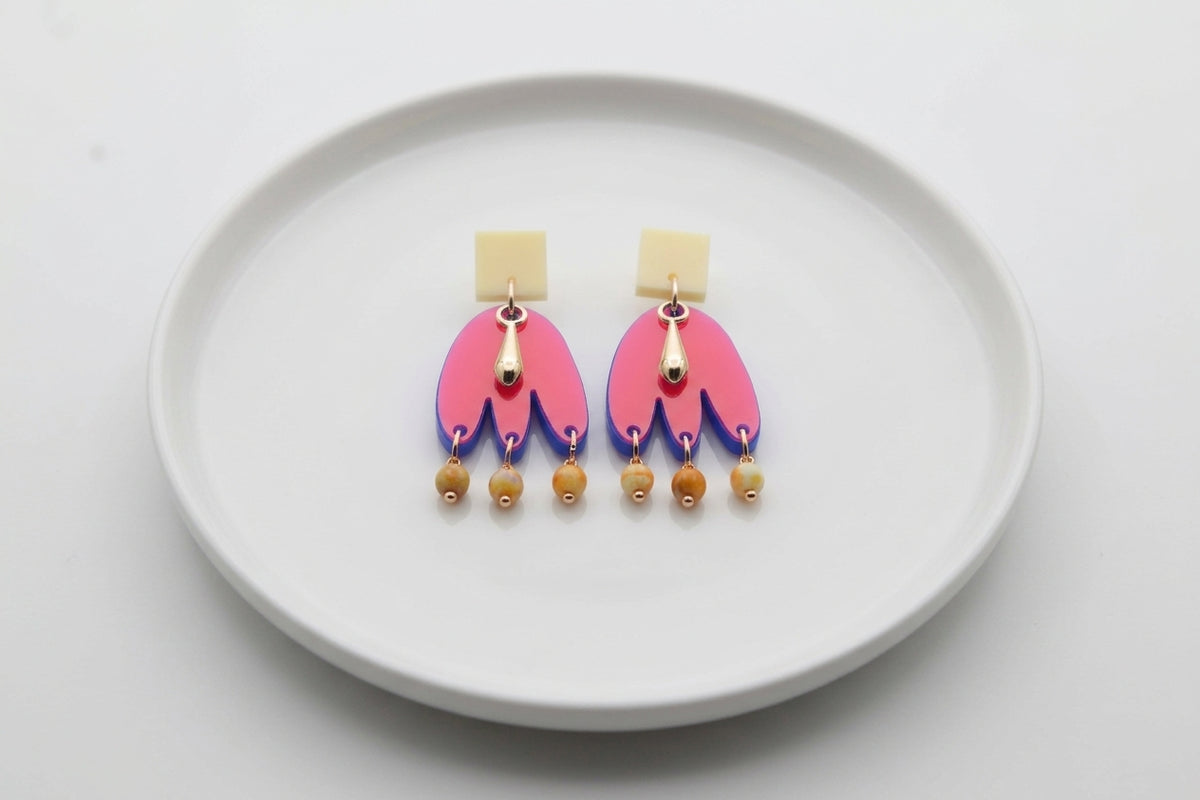 HB Liv acrylic beaded statement earrings arranged on a white plate