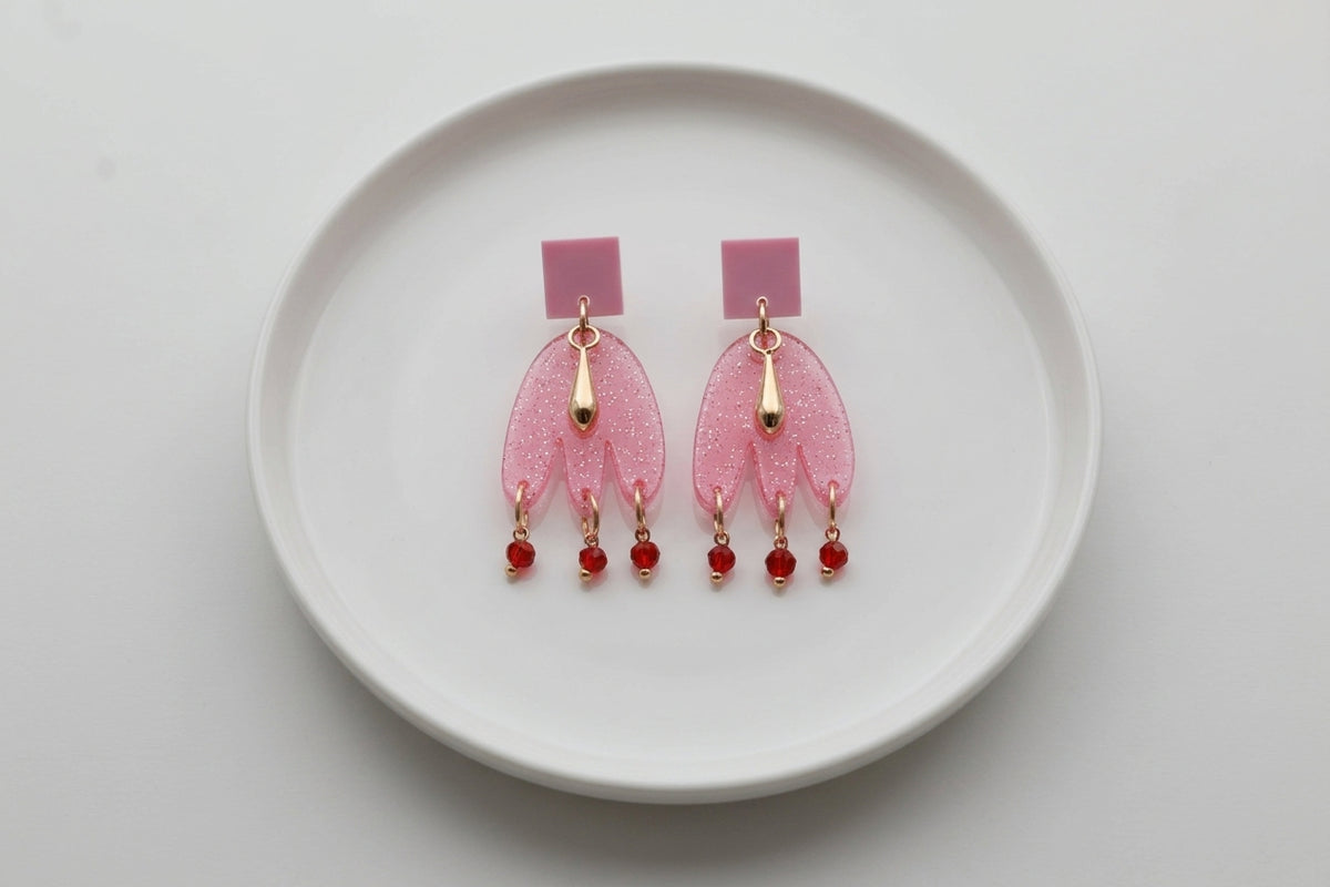 Pink Liv acrylic beaded statement earrings arranged on a white plate