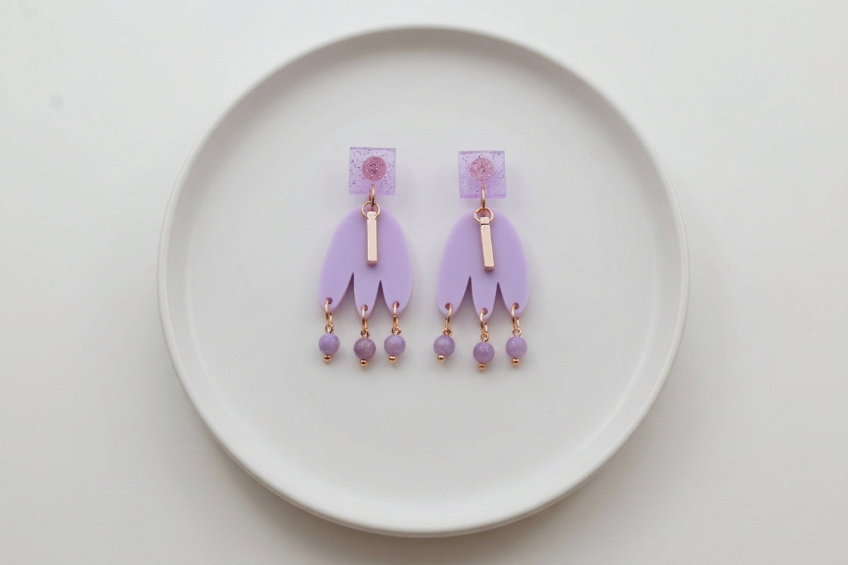 Purple Liv acrylic beaded statement earrings arranged on a white plate