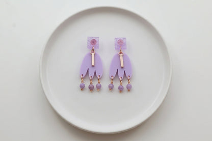 Purple Liv acrylic beaded statement earrings arranged on a white plate