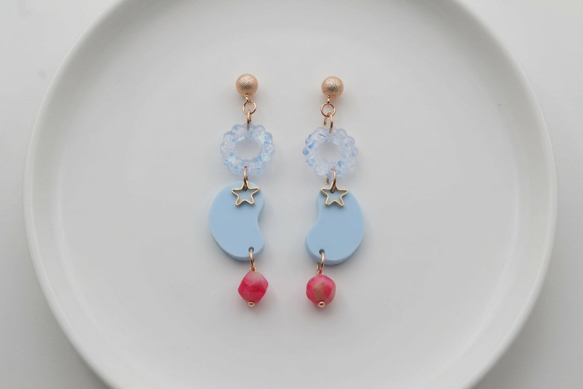Blue Lucia floral star dangle earrings arranged on a white plate