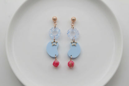 Blue Lucia floral star dangle earrings arranged on a white plate