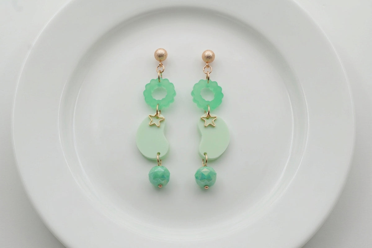 Green Lucia floral star dangle earrings arranged on a white plate