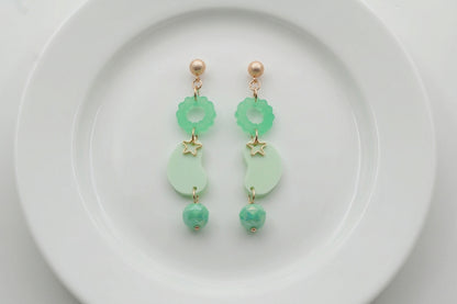 Green Lucia floral star dangle earrings arranged on a white plate