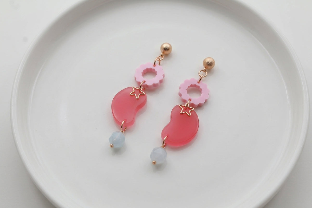 Pink Lucia floral star dangle earrings arranged on a white plate