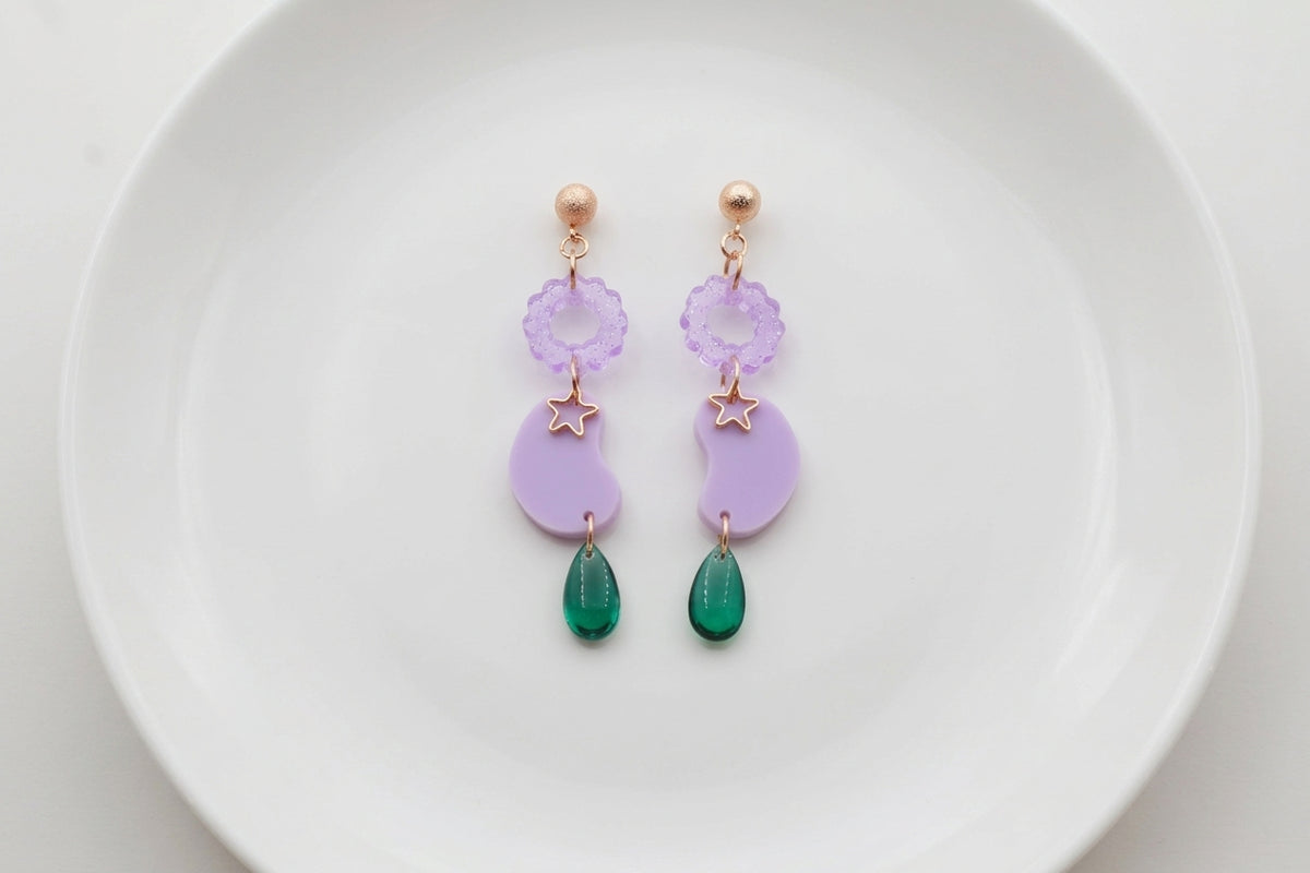 Purple Lucia floral star dangle earrings arranged on a white plate