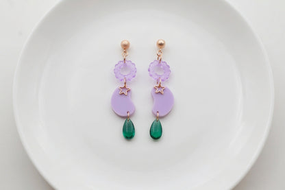 Purple Lucia floral star dangle earrings arranged on a white plate