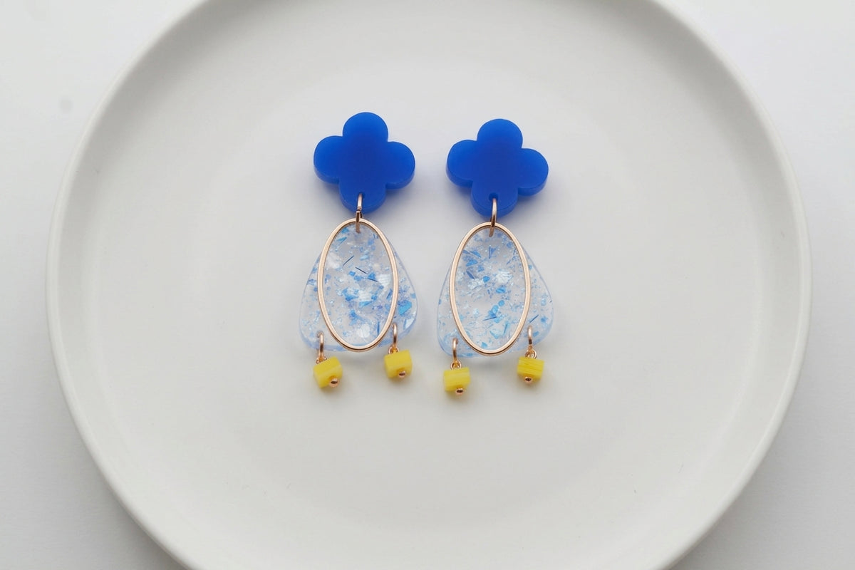 Blue Maud flower statement earrings arranged on a white plate