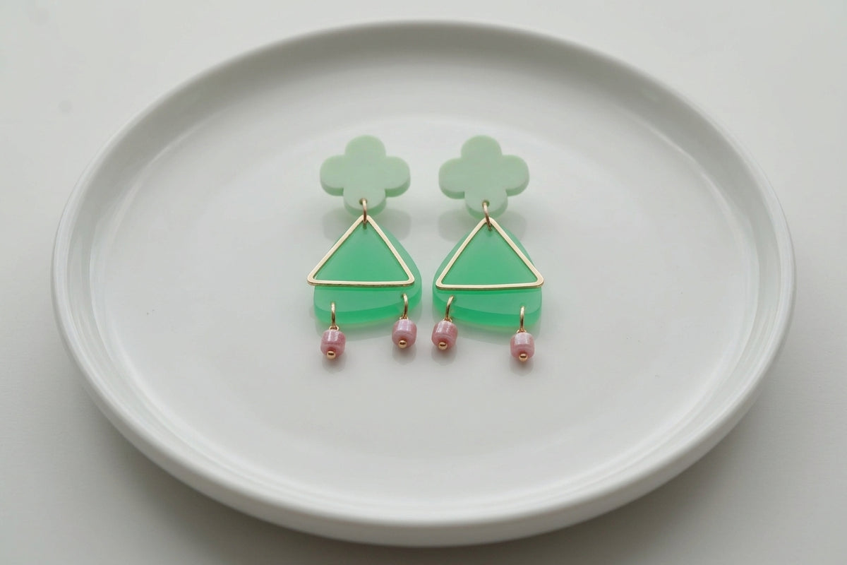 Green Maud flower statement earrings arranged on a white plate