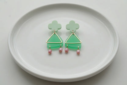 Green Maud flower statement earrings arranged on a white plate