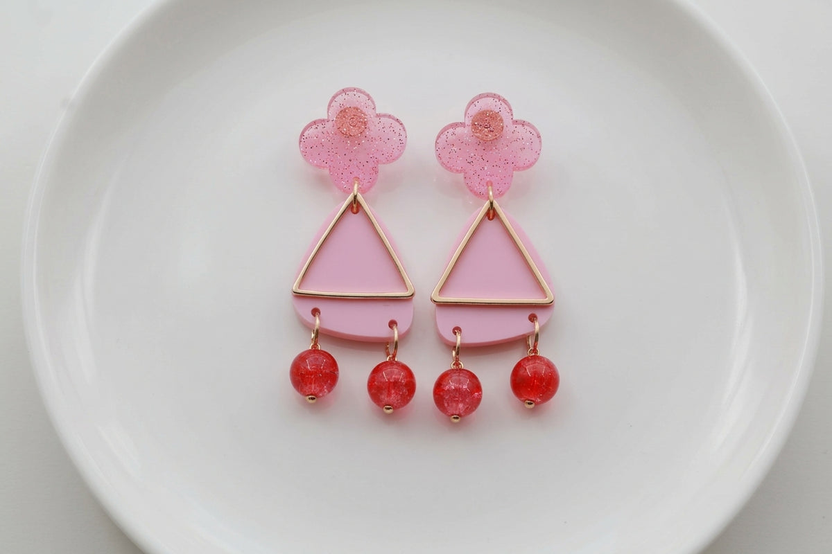 Pink Maud flower statement earrings arranged on a white plate