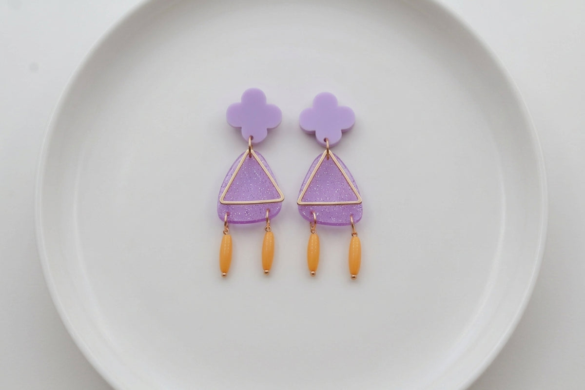 Purple Maud flower statement earrings arranged on a white plate